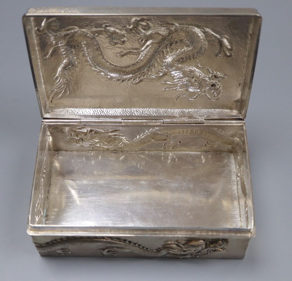 An early 20th century Chinese Export white metal cigarette box, embossed with a dragon, by Wang Hing, 13cm, gross 9oz.